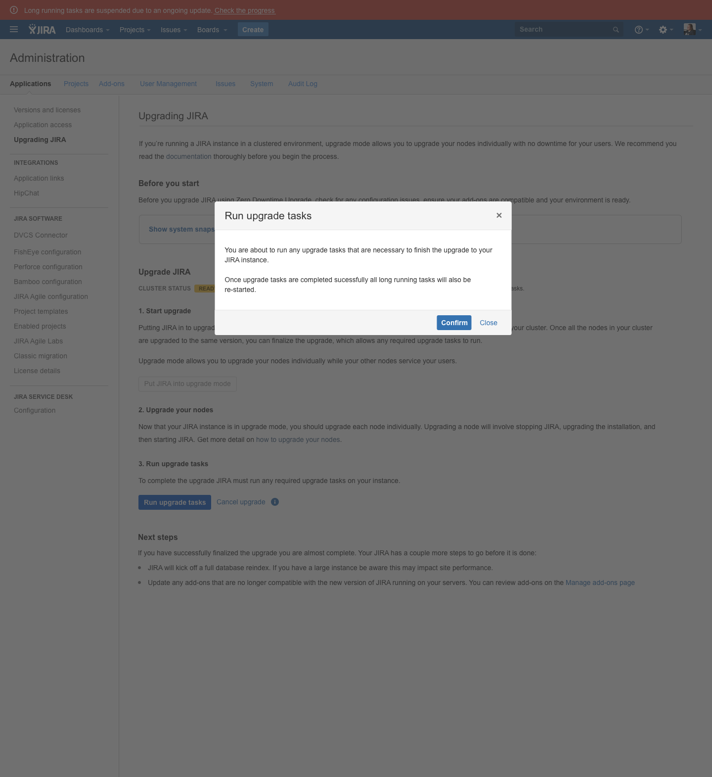 Jira Data Center 'Upgrading JIRA' administration page with a centered 'Run upgrade tasks' confirmation modal: a red suspended-tasks banner across the top, the page dimmed by an overlay, the cluster status lozenge reading 'READY TO UPGRADE', a disabled 'Put JIRA into upgrade mode' button, and the modal body explaining that upgrade tasks will run and long-running tasks will restart, with a blue Confirm button and a Close link.